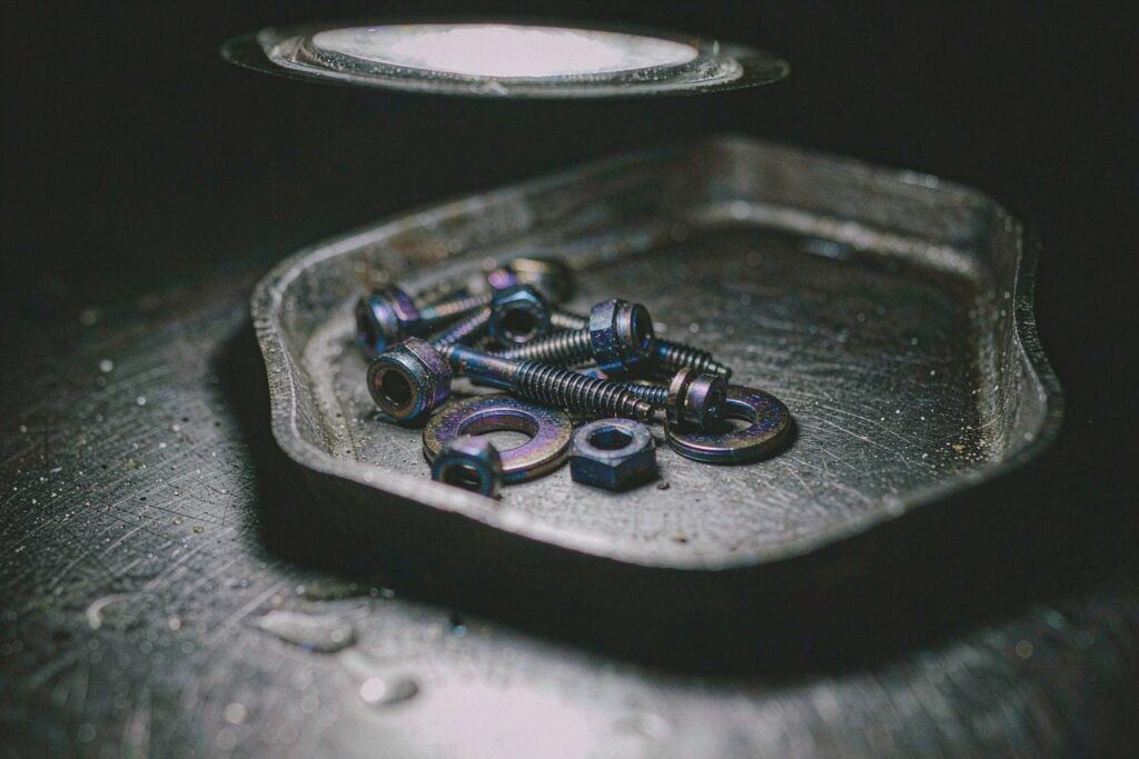 Anodised titanium bone screws and washers on a steel bench showing blue, violet and bronze thin-film interference colours