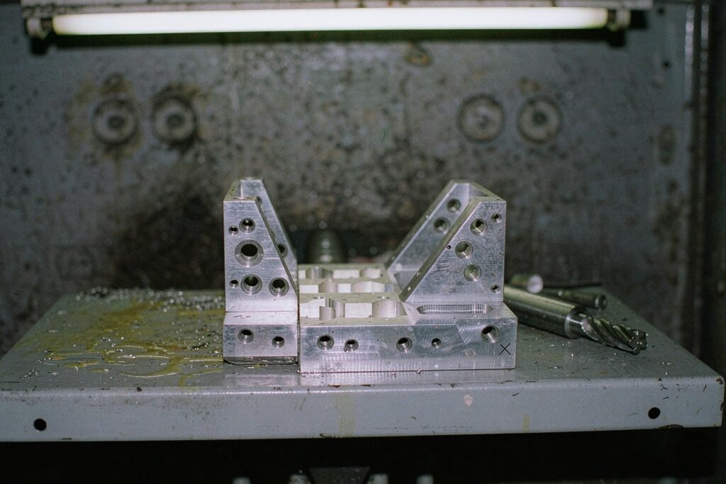 Complex machined brackets with angled mounting faces, milled lightening pockets and holes on three planes on a steel worktable